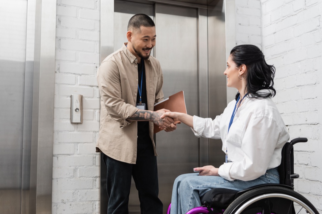 Man shaking hands with a woman in a wheelchair