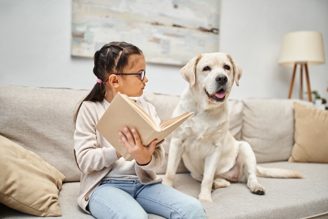 Child reading to dog on the couch