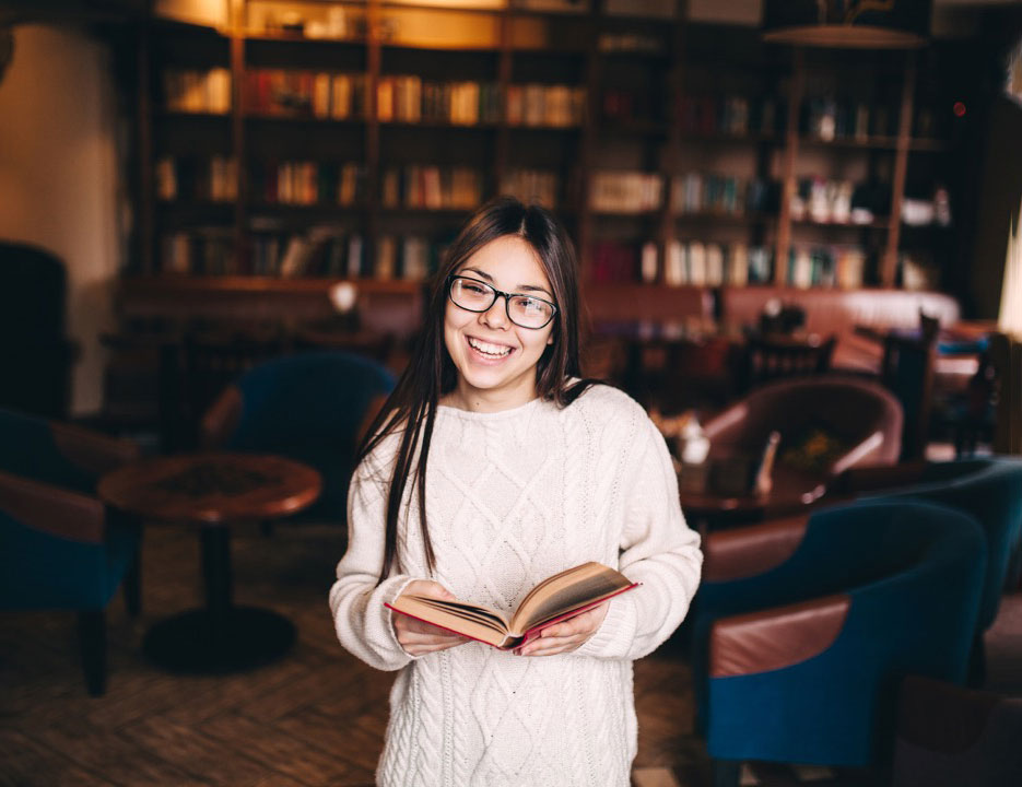 Student holding a book in a library