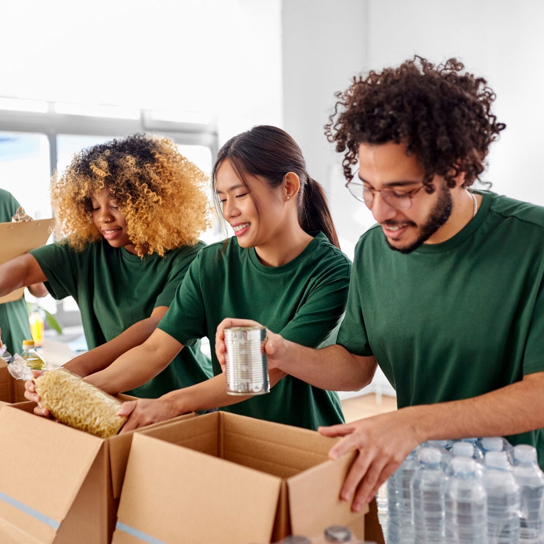 Three teens gather food in a box