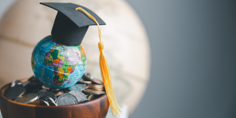 Globe with graduation hat laying on top of it