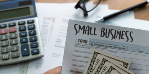 a person holding up a paper that says "small Businesss"